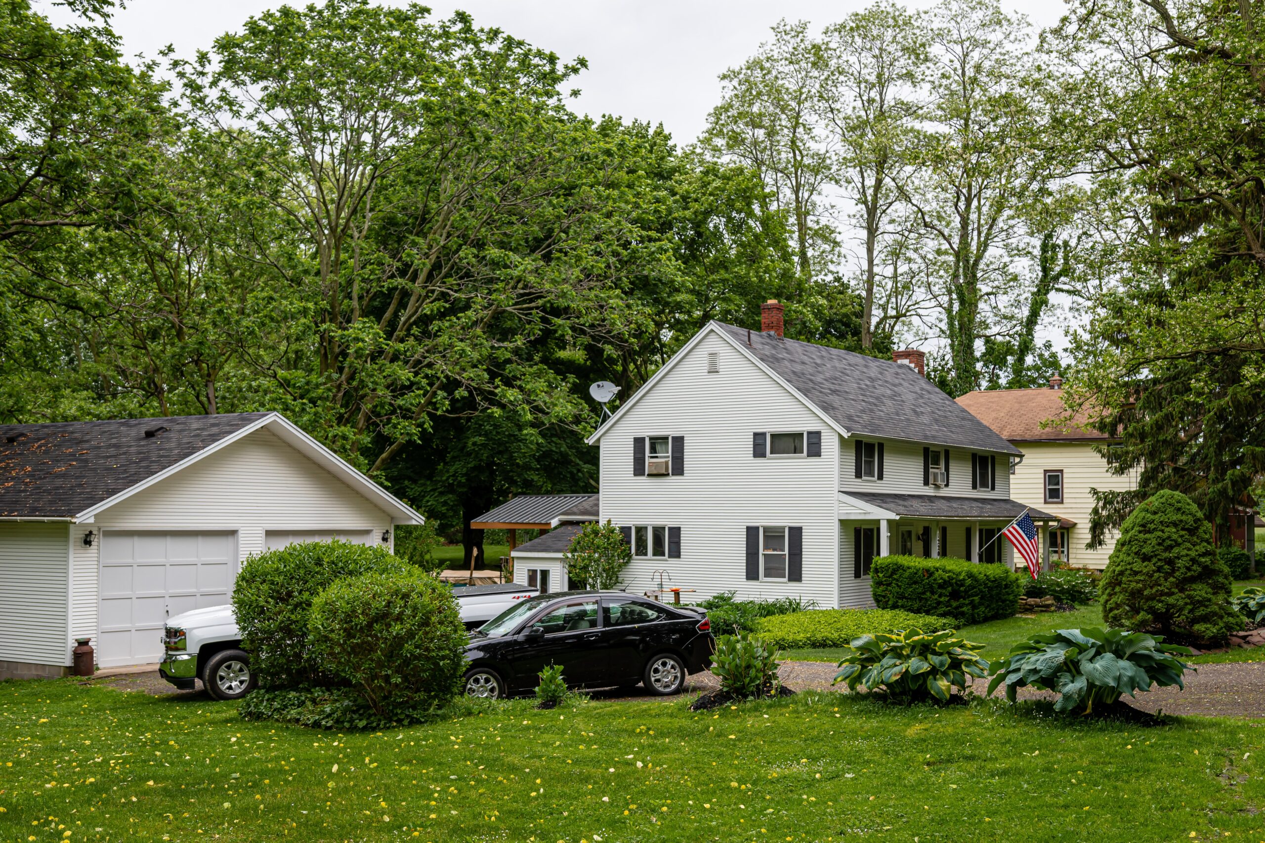 White home with American Flag and two cars in the front yard